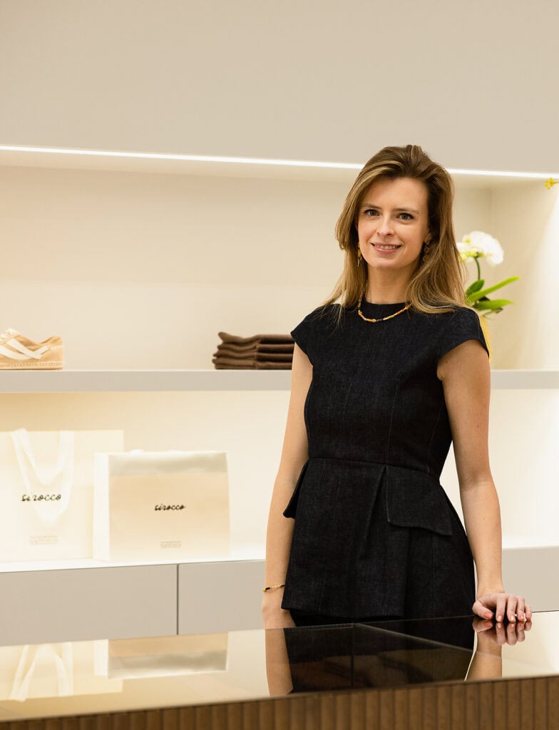 Vrouwelijke medewerker bij Sirocco in een winkel met producten op de achtergrond.