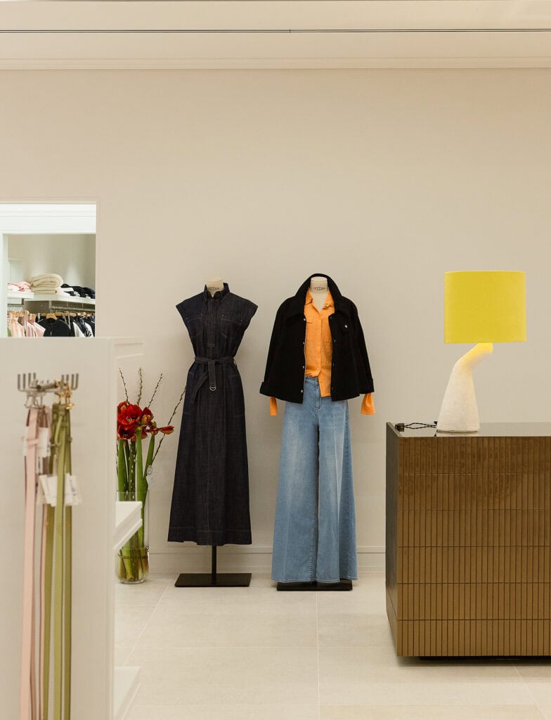 Modellen in een boetiek met jurken en casual outfits.