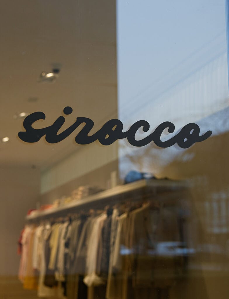 Sirocco winkel met kledingrekken en logo op raam.