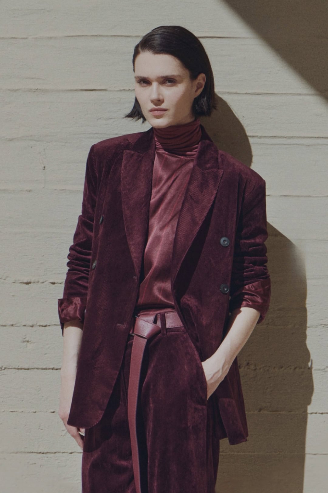 Modieuze vrouw in dieprode velvet blazer en broek.