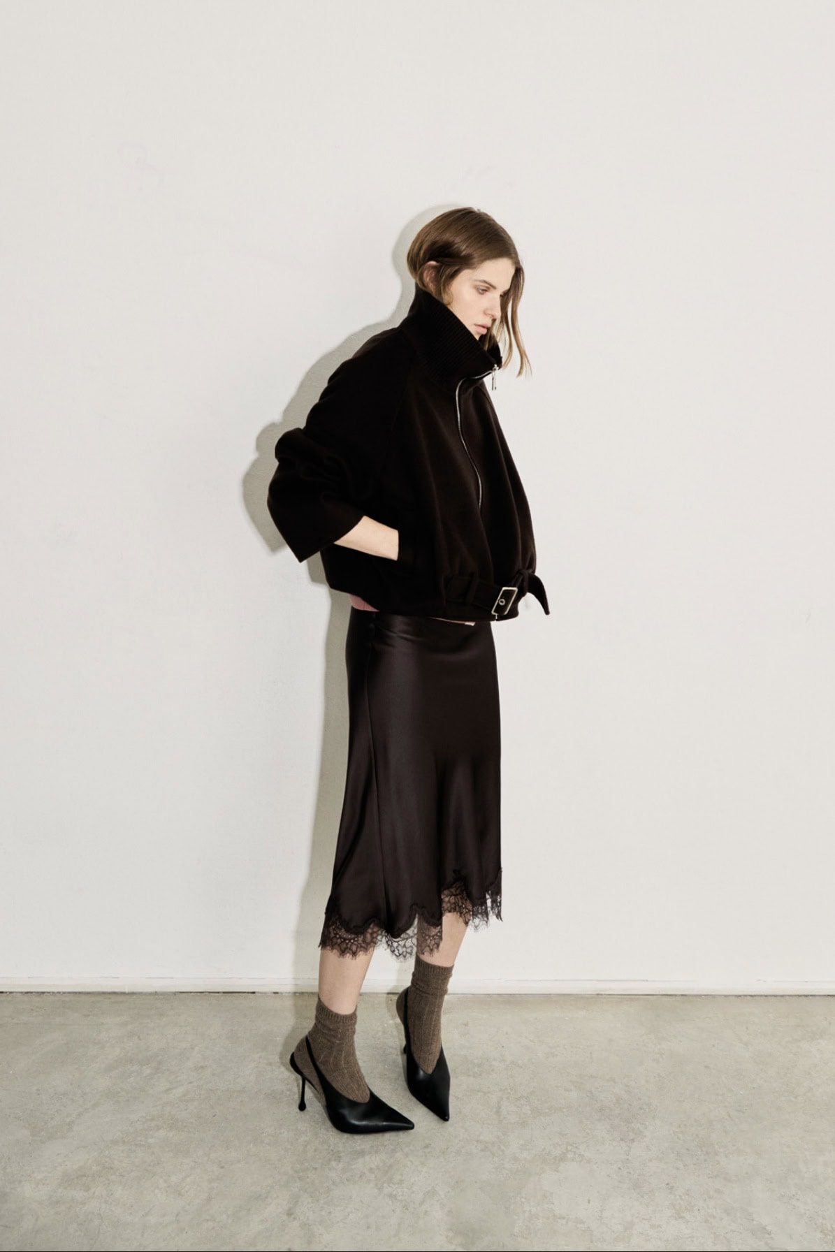 Modieuze vrouw in zwart jasje en kanten rok voor elegante uitstraling.