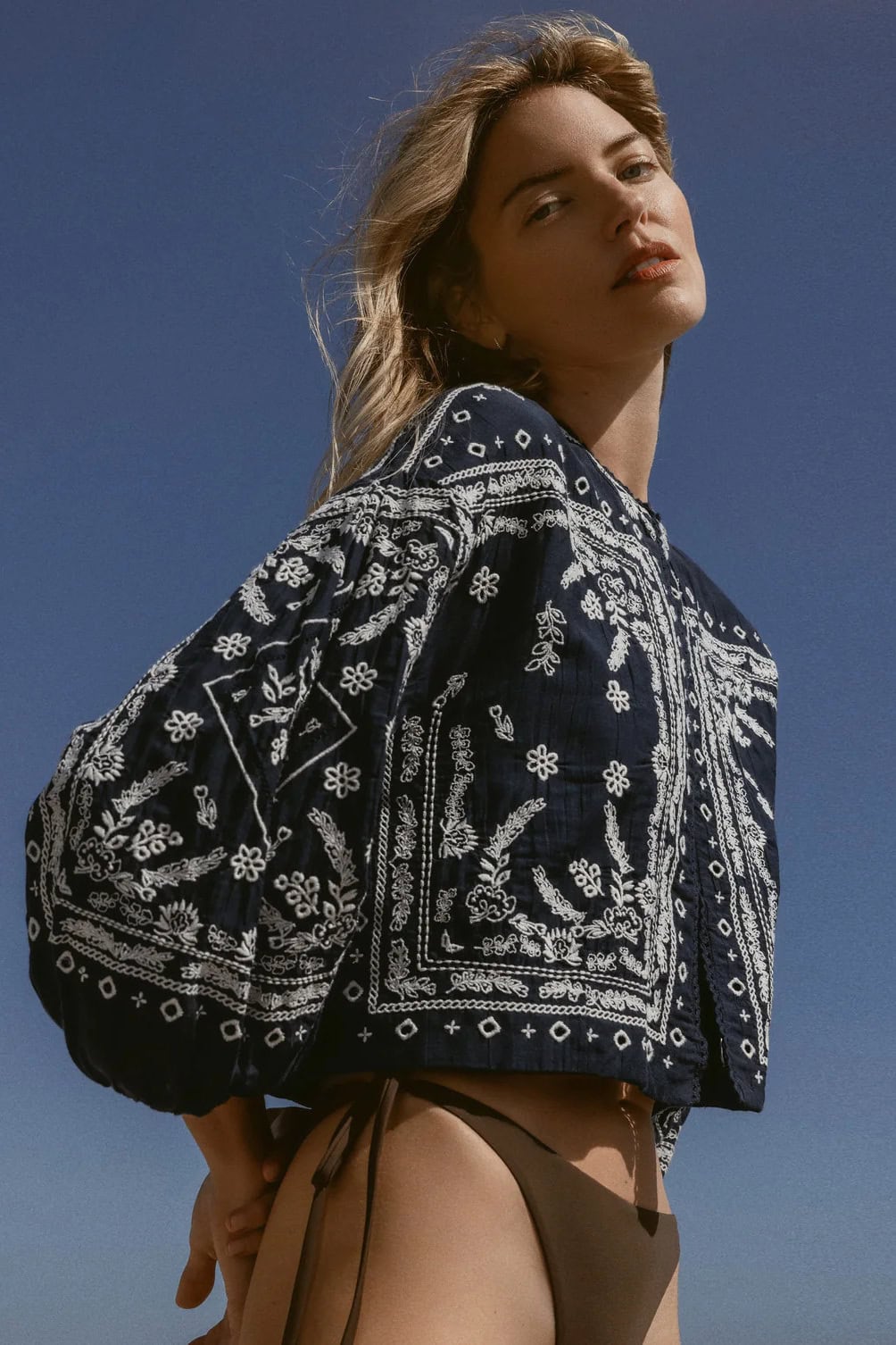 Modieuze vrouw in Sirocco kleding met blauwe lucht achtergrond.